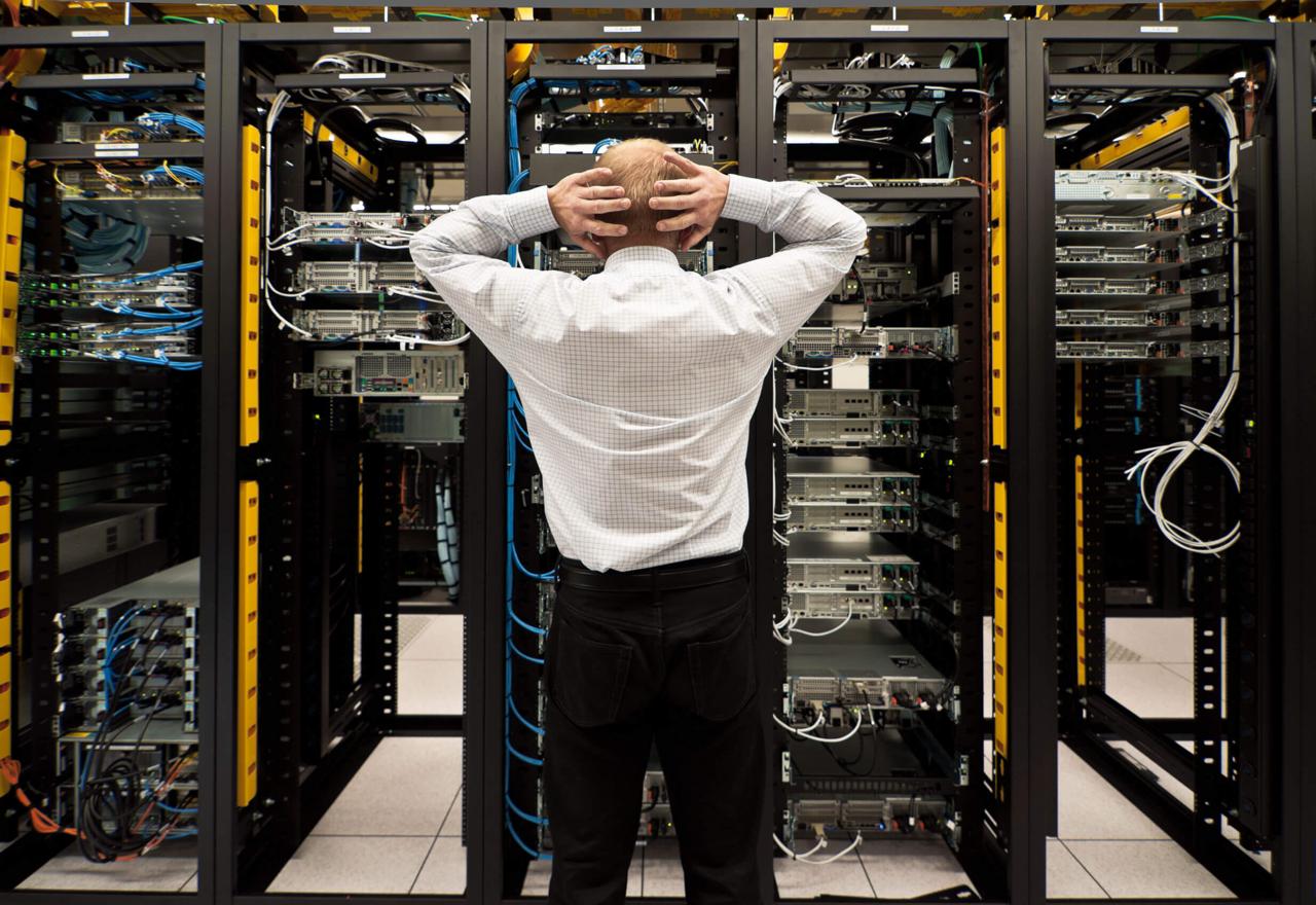 Man standing in a server room with hands on his head